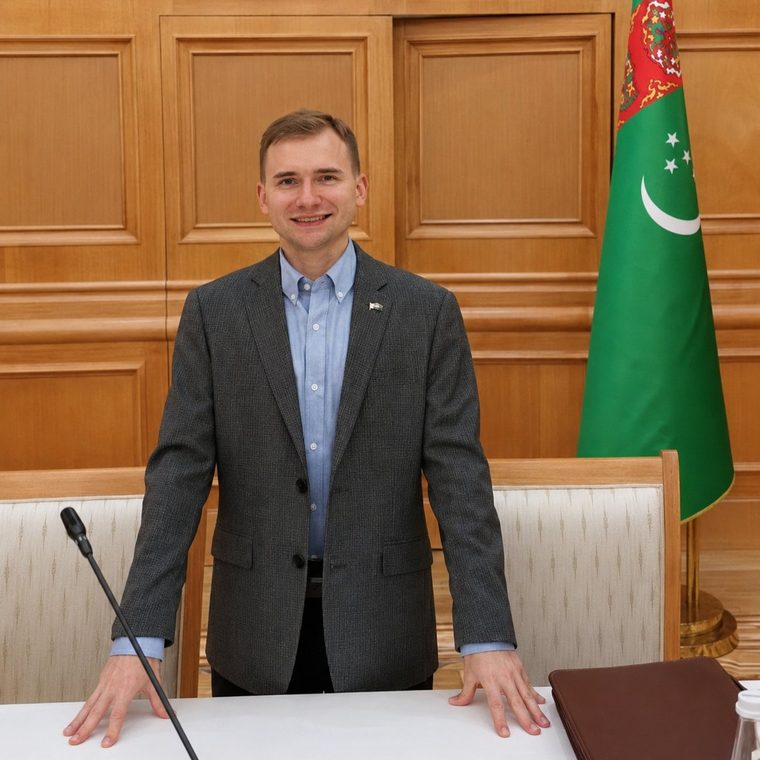 Christopher Wizda at a meeting beside the Turkmenistan state flag